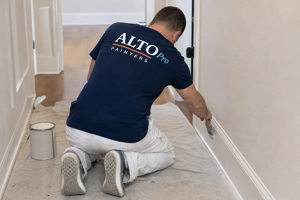 Painter painting baseboards in a hallway, interior painting in Kaleden